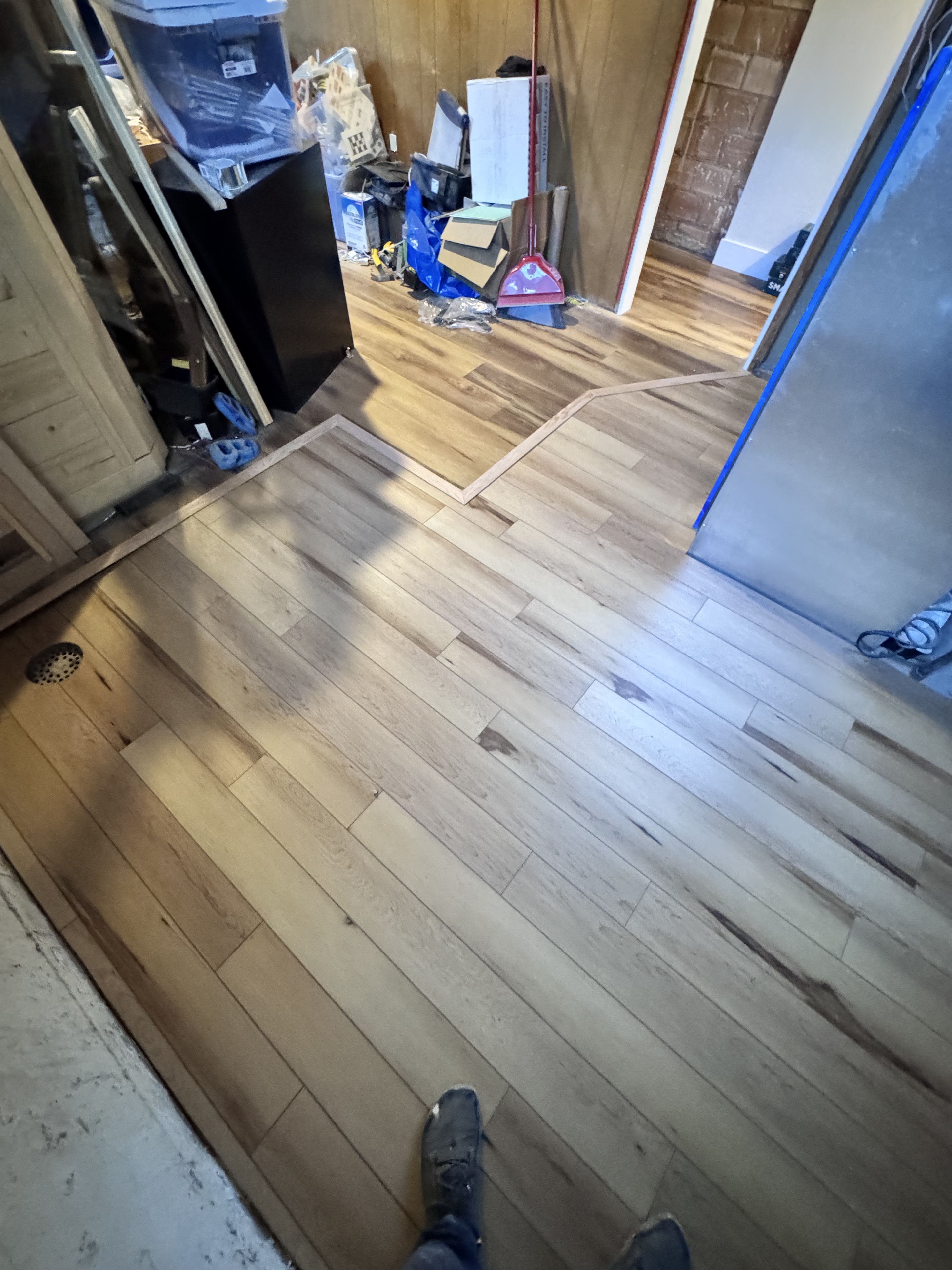 Completed light wood-look flooring through a room and hallway